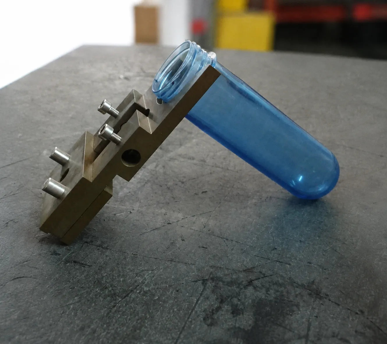 Technische Demonstration der Platzierung eines blauen Kunststoff-Preforms in einen speziell entwickelten Metallform-Kern-Einsatz und Detail der Formmontagephase in der ARK CNC-Anlage in Istanbul