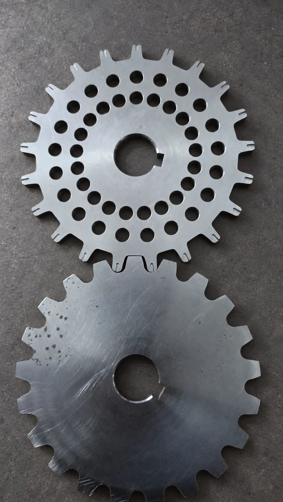  Çevresinde dişler ve merkezinde kama kanalı bulunan, biri çok delikli iki CNC işlenmiş metal disk