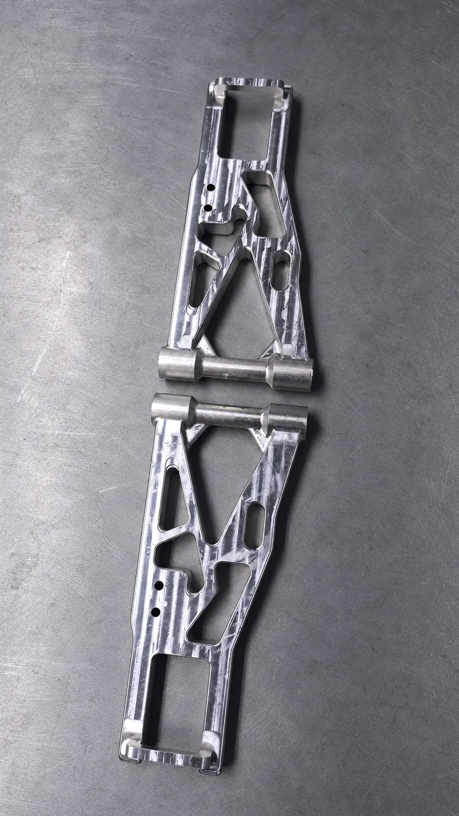 Üçgen ve dikdörtgen açıklıkları, oval cepleri ve bağlantı delikleri bulunan iki CNC freze işlenmiş metal kol